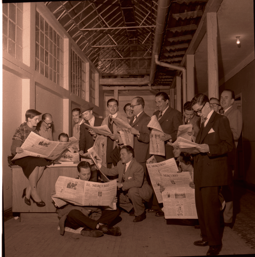 Es probable que sea foto del personal de la emisora HJCK. Todos están leyendo el periódico 'El Mercurio', periódico donde Caicedo trabajó brevemente a inicios de la década de 1950. En la foto, se identifica a Gloria Valencia de Castaño (1927-2011) en el extremo izquierdo de la foto, sentada. Valencia de Castaño fue periodista y presentadora de televisión y en 1950 fundó, junto con su esposo Álvaro Castaño Castillo, la emisora HJCK. Circa 1953.

Referencias:
Daniel Samper Pizano,Carlos Caicedo: fotógrafo de prensa, Catálogo de exposición, Bogotá: MAMBO, 1976, s.p.
Wikipedia, entrada Gloria Valencia de Castaño, consultada el 13 de junio, 2023.